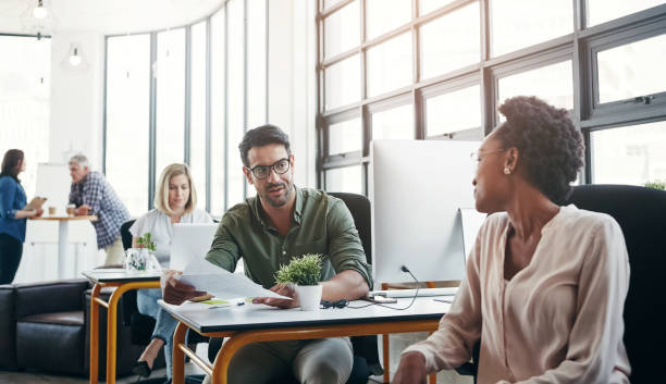 istock Office, business and colleagues talking or in discussion while working on a project in a coworking space. Interracial, communication and corporate employees in a conversation or consult in workplace. 2156915923