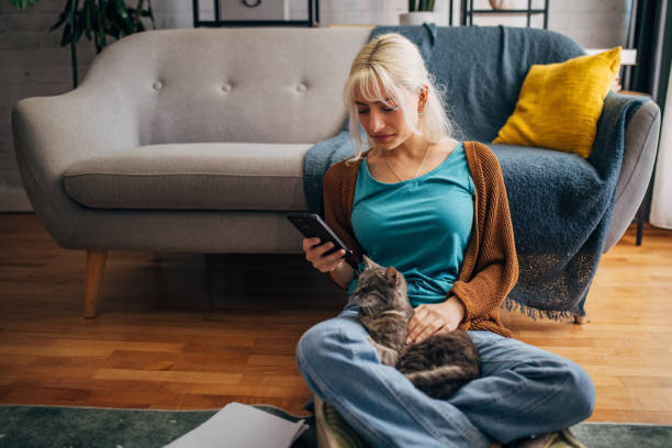 istock Young white blond girl using a smart phone and petting a cat 2156918213