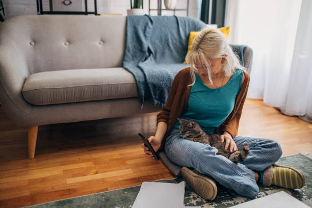 istock White girl using a smart phone and petting a cat 2156918502