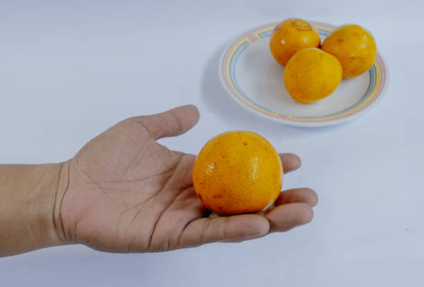 Man hand holding orange fruit on white background. Orange fruit on a small plate.