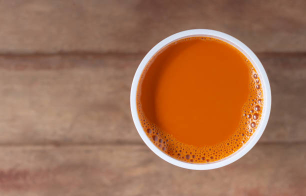 Hot milk tea in a white cup on wooden table blurred background