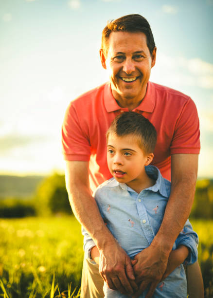 Father and son hugging and playing together in green nature.