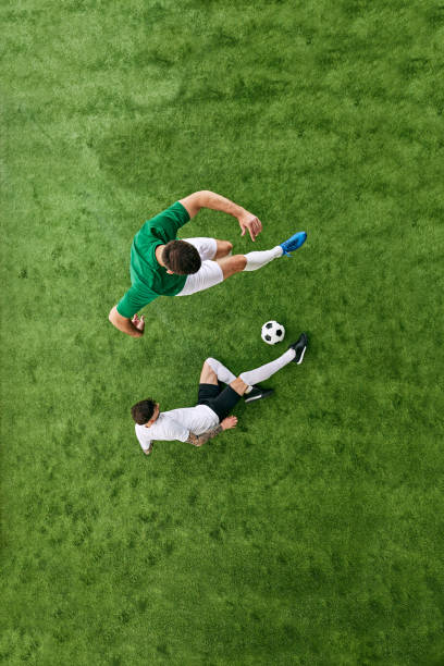 istock Aerial view of player in green attacking, while player in white defending on green lush playground. Football match. 2156924190