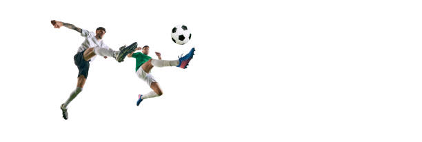 istock banner. Player in green kicking it forward, and player in white making defensive move to stop him against white background with copy space. 2156924218
