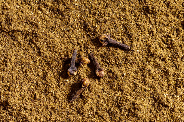 Dry cloves on clove powder background top view