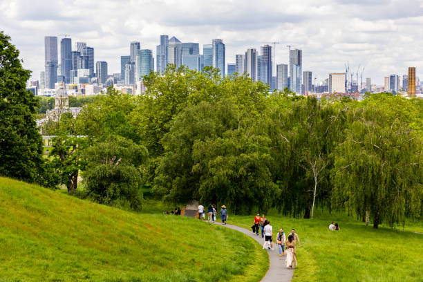 United Kingdom, London, Greenwich park - 05.25.2024\nPeople walking in Greenwich park, in a Spring day, with skyscrapers panorama behind