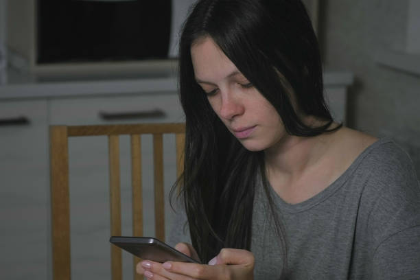istock Single young woman types a message at night in the kitchen. 2156941520