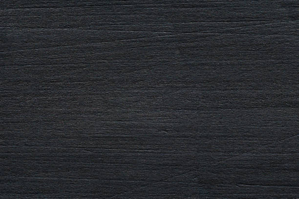 High angle view of a flat textured wooden board backgrounds. It burnt and black colored with fire skill. It is carbonization the surface. It has a beautiful nature and abstractive pattern. A close-up studio shooting shows details and lots of wood grain on the wood table. The piece of wood at the surface of the table also appears rich wooden material on it. The wood is black and pattern on the bottom. Flat lay style. Its high-resolution textured quality. The close-up gives a direct view on the table, showing cracks and knotholes in the wood.