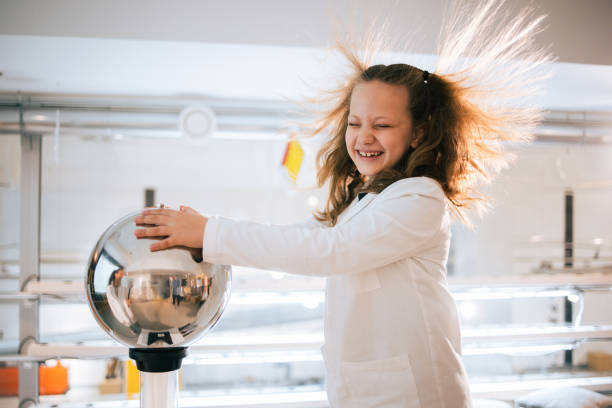 Young girl having fun with a static electricity experiment, causing her hair to stand on end in a science lab.