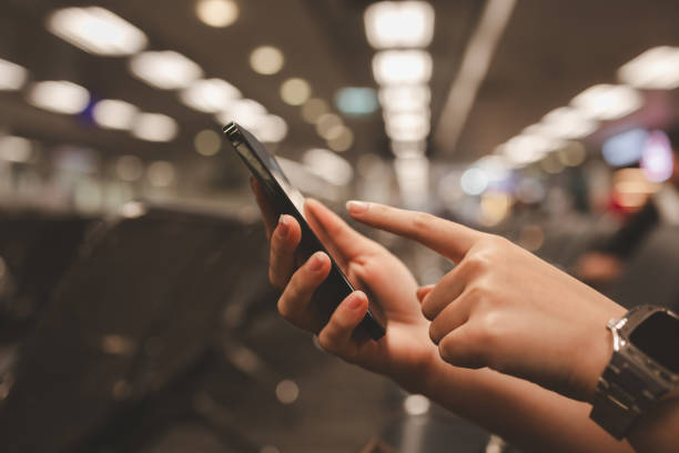use the smartphone to check how long when the flight will be ready, sitting in the airport and checking in online via mobile phone, traveler takes a flight to go on vacation abroad