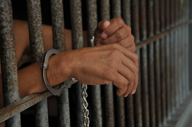 istock close up of prisoner hands in jail background. 2156955145