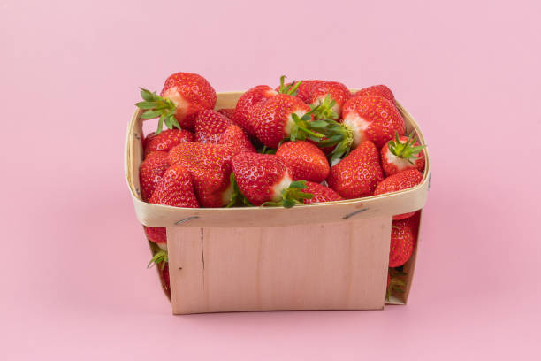 istock punnet of strawberries, close-up, on a pink background 2156955804