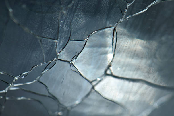 A radiating pattern of cracks and shatters in a clear sheet of glass, backed by vivid royal blue. Great backround or texture.