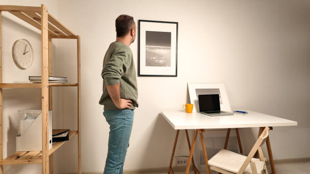 istock Man hanging pictures on the wall. 2156963727
