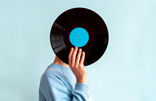 istock Man in  blue sweatshirt covers his face with vinyl record on blue background 2156963978