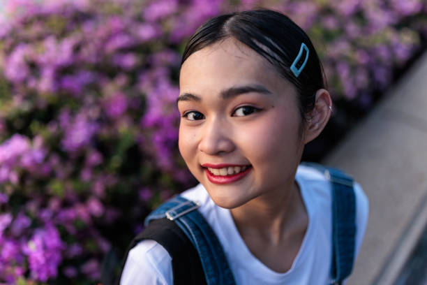 Portrait of a Thai teenage woman sitting by the flowers in Benjakitti park in Bangkok.