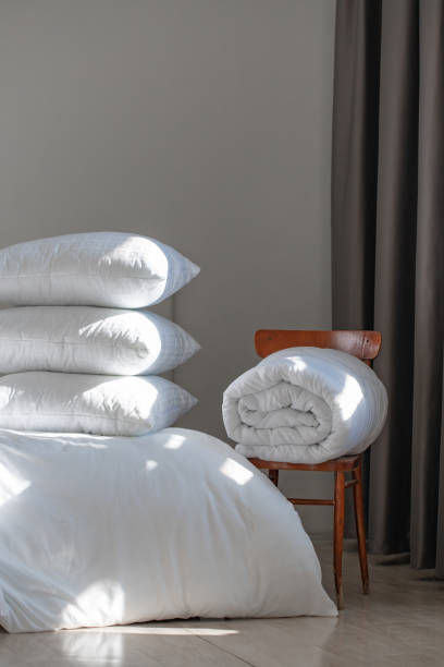 istock A bed with white pillows and a blanket, next to a bedside table with a lamp, daylight 2156967925