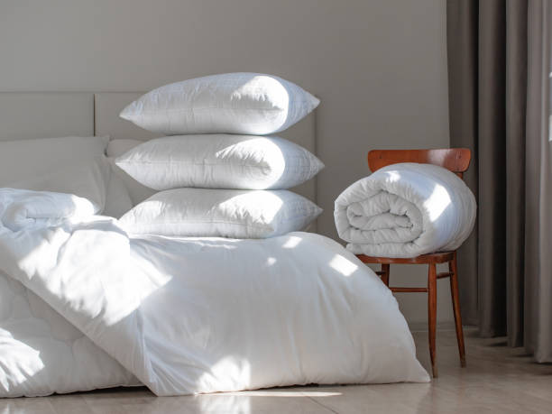 istock A bed with white pillows and a blanket, next to a bedside table with a lamp, daylight 2156967930