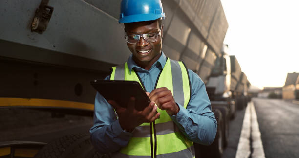 istock Construction worker, man and tablet by truck for logistics with vehicle inspection for shipping and cargo export. Transport industry, site manager or black employee with app for maintenance and happy 2156970890