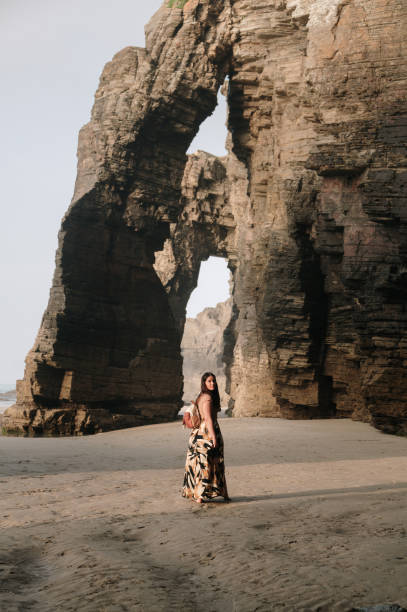 istock Woman walking on a beach with natural rock arches 2156980302