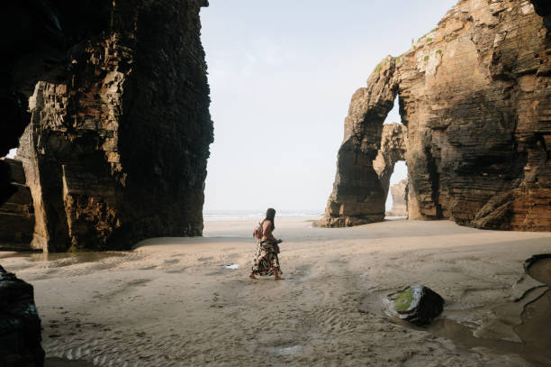 istock Woman walking on a beach with natural rock arches 2156980458
