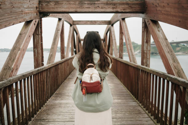 Rear view of a woman with a bag on a pedestrian bridge made of wood