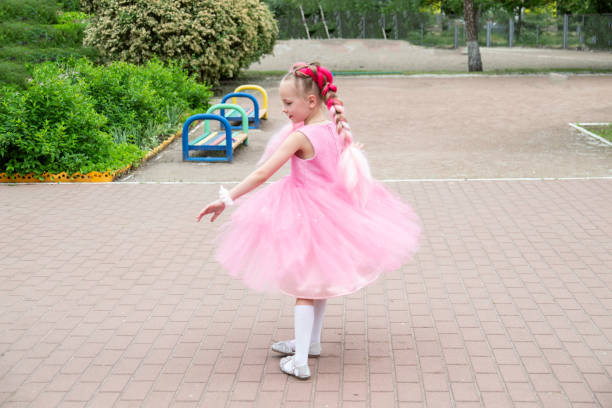 Ballerina profile, with pink tutu, holding her pointe.