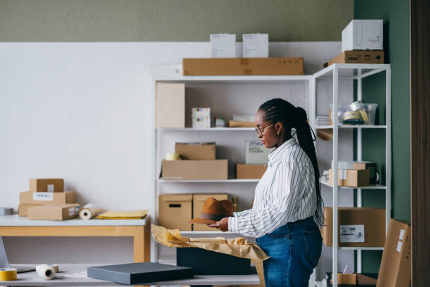 istock Woman Packaging Hat in Small Business Warehouse 2156987648