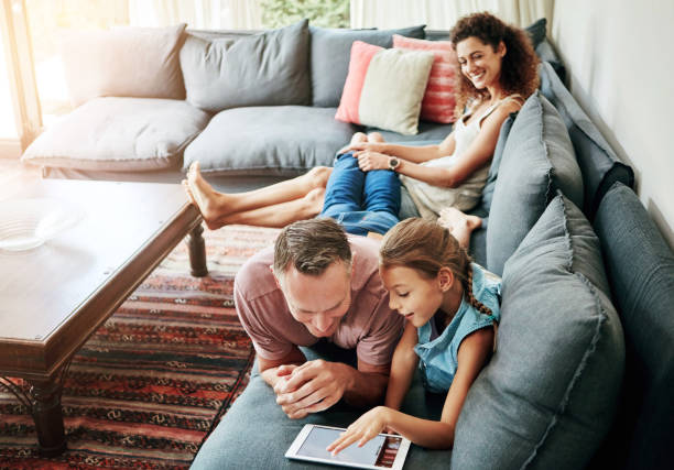 istock Mother, father and child with tablet in watching on weekend, break at home for e learning or gaming. Happy people, lounge and relax in together for bonding as parents for growth, development and love 2156996769