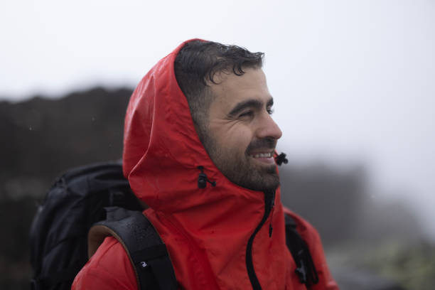 Heavy rain during autumn day. Portrait of young man in waterproof jacket.