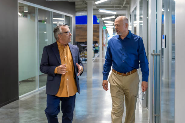 istock Two men walking and talking in a corporate hallway 2157004317