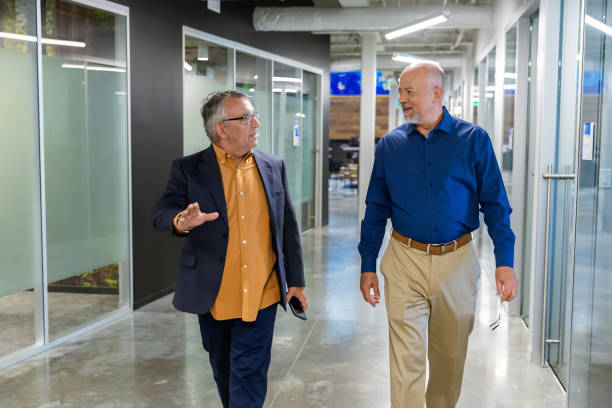 istock Two men walking and talking in a corporate hallway 2157004318