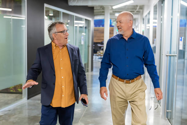 istock Two men walking and talking in a corporate hallway 2157004334