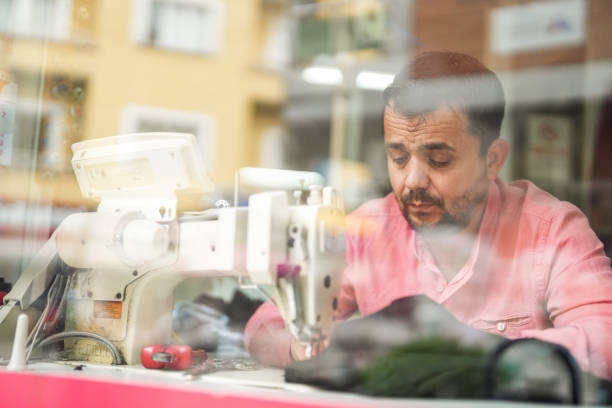 man tailor sewing in a small tailor shop.