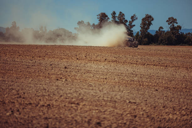 Agricultural activity and organic farm in Italy: tractor at work in the field, plowing a dusty ground