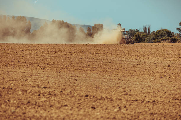 Agricultural activity and organic farm in Italy: tractor at work in the field, plowing a dusty ground