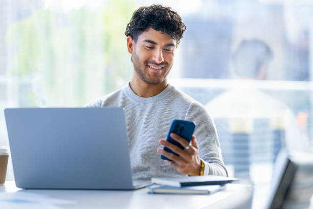 istock Businessman working on a laptop computer and texting or using social media on a mobile phone in the office. 2157008122