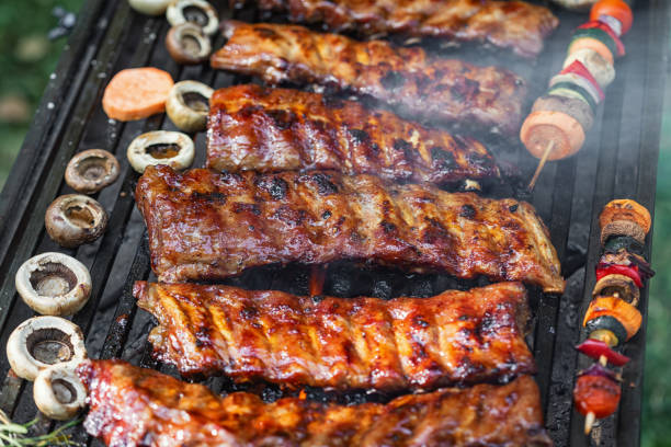 A spread of meat over a smoky backyard barbecue pit.