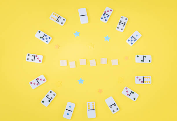istock White dominoes with colored dots and empty wooden cubes on a yellow background. 2157010582