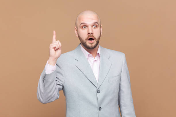 istock Man raising index finger, having bright idea or interesting thought, wearing gray jacket. 2157014208