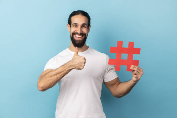 istock Man holding hashtag symbol, showing thumb up, recommending popular topics, internet trends. 2157015101