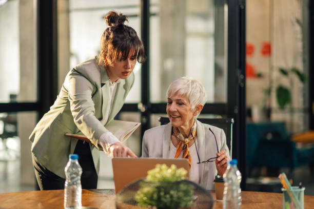 istock Senior female executive discussing project on laptop with secretary. 2157016207