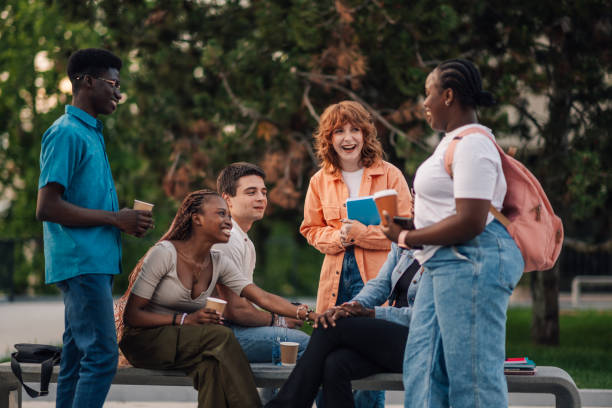 Interracial college boys and girls chatting at campus during break.