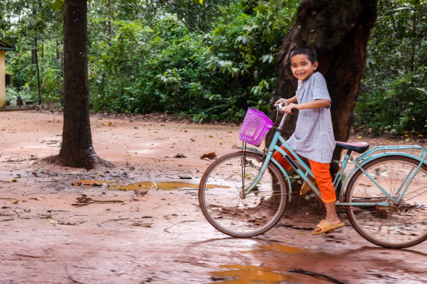 Happy Cambodian boy is riding a bicycle in village near Siem Reap, Cambodia