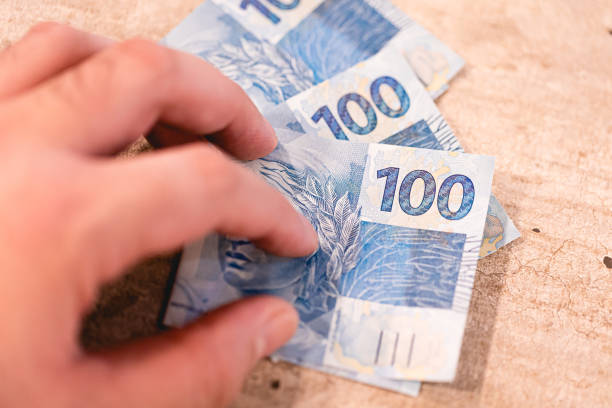 istock A man holding 100 Brazilian Real notes. Closeup photo. 2157020393
