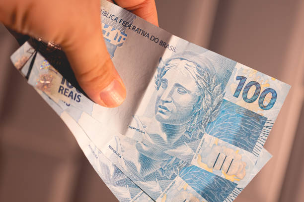 istock A man holding 100 Brazilian Real notes. Closeup photo. 2157020446
