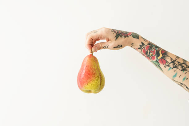 istock Tattooed hand holding a fresh red blush pear 2157021490