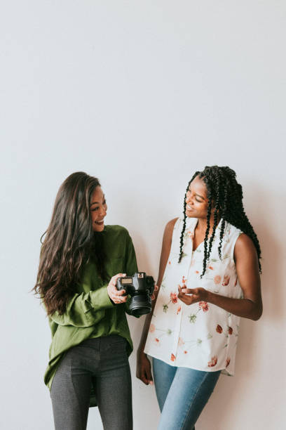 istock Happy women with a digital camera talking 2157024465