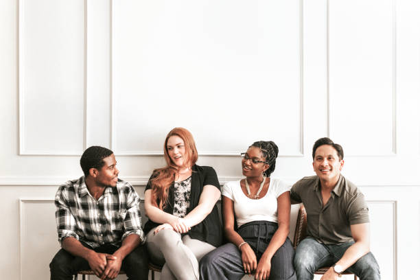 Happy people sitting by a white wall