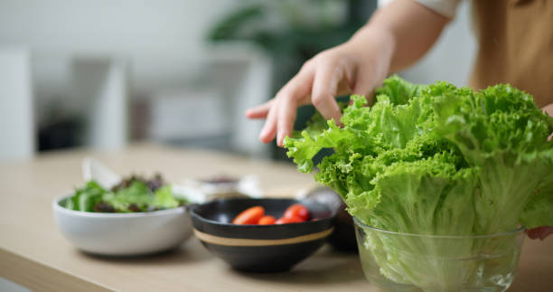 istock Young woman's hands arranging vegetables to make salad in the home kitchen. 2157033106